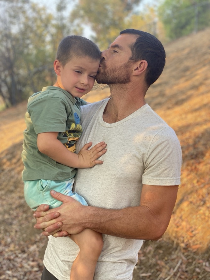 Jared kissing his son's head on a golden hillside