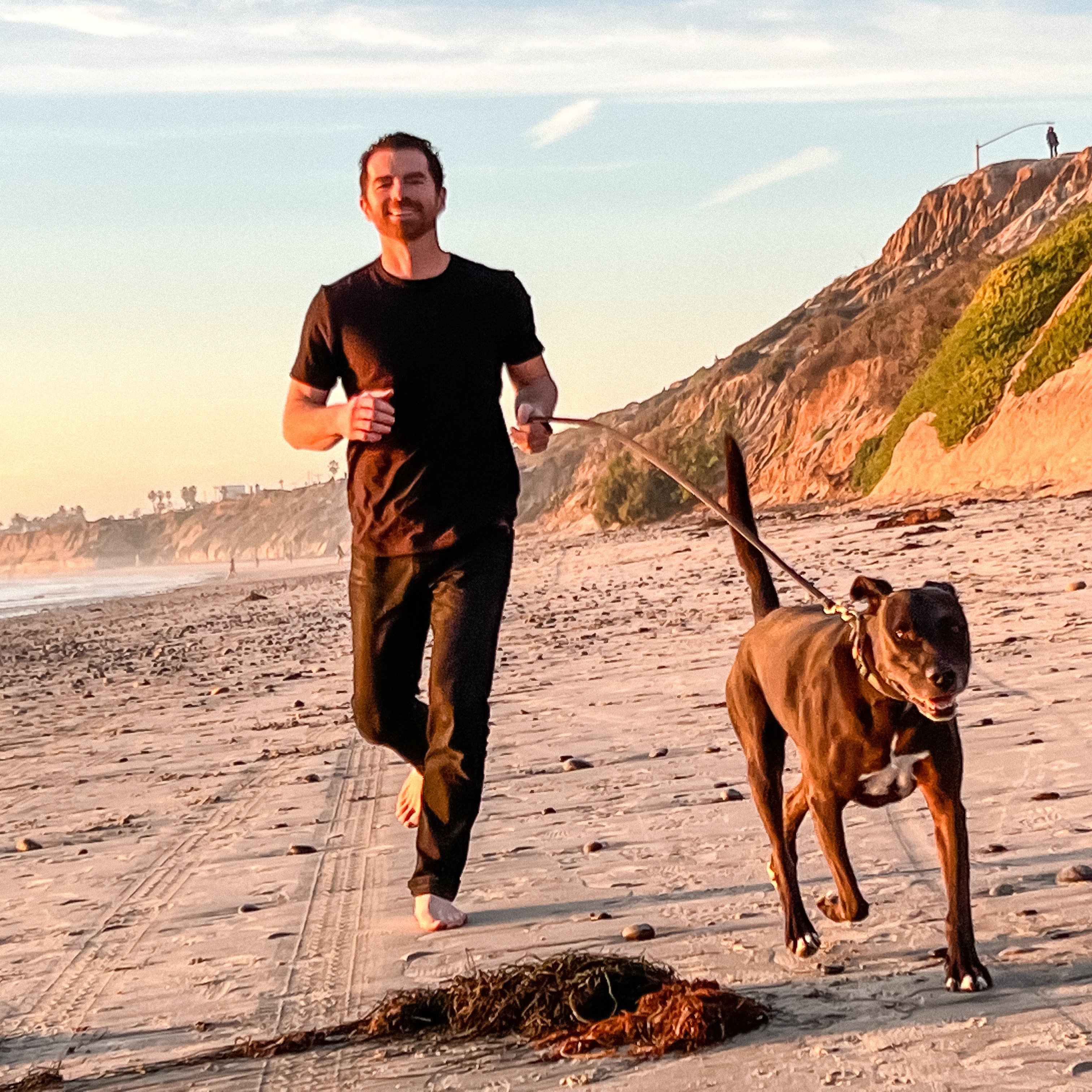 Jared running on the beach with his dog at golden hour